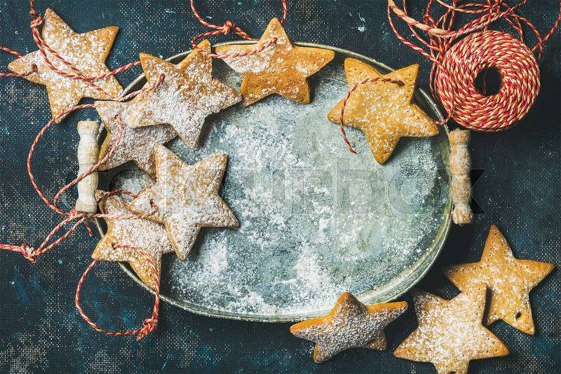 Christmas holiday star shaped gingerbread cookies for Christmas tree decoration with red ropes in vintage metal tray over dark blue plywood background, top view, copy space, horizontal composition, stock photo