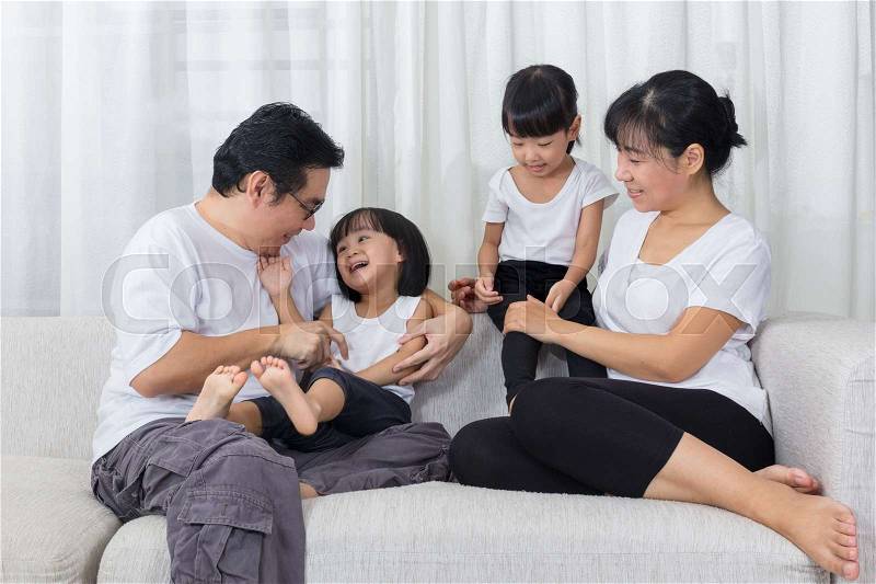 Happy Asian Chinese family sitting on the couch in the living room at home, stock photo