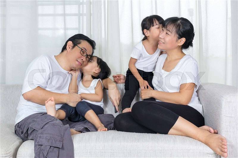 Happy Asian Chinese family kissing on the couch in the living room at home, stock photo