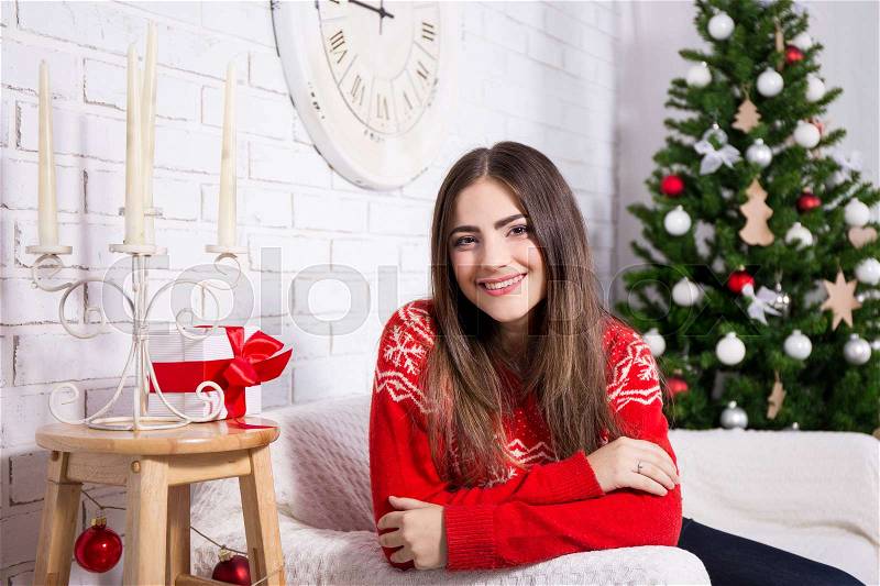 Happy young beautiful woman in decorated living room with Christmas tree, stock photo