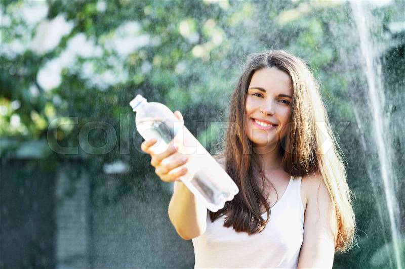 Beautiful young woman drinks water from a bottle, stock photo