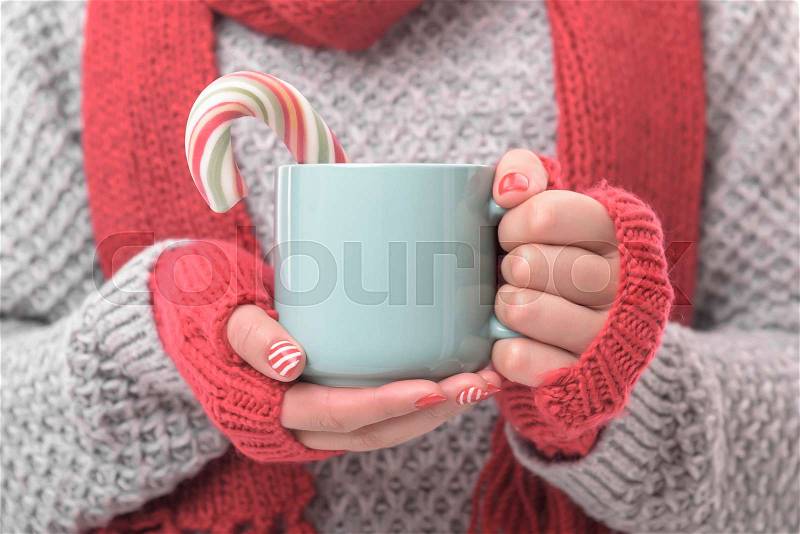 A cup with a drink and a Christmas candy in the hands. Close-up, stock photo