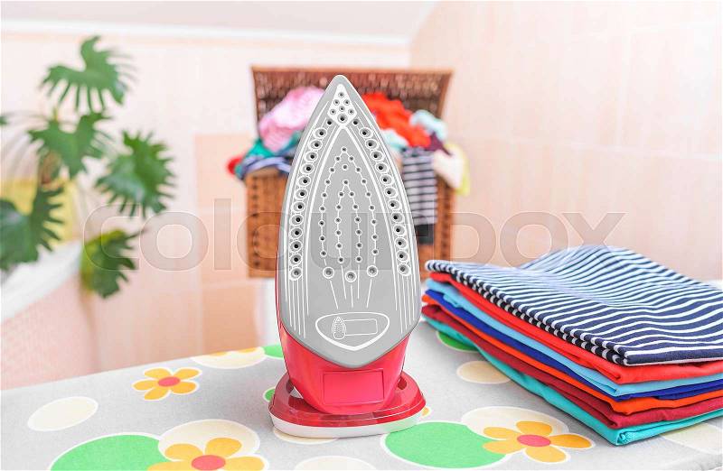 Iron and ironed clothes on an ironing board, stock photo