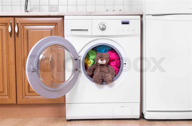 Teddy bear in a washing machine. Preparing the wash cycle, stock photo