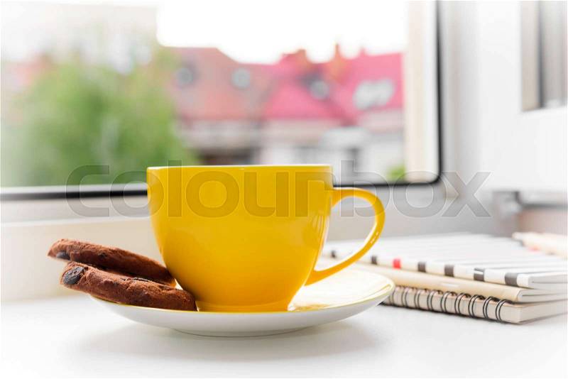 Cup of tea and a notebook on a window, stock photo