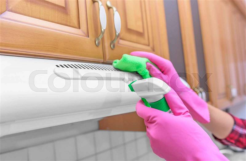 Female hands with gloves are washed cooker hood in the kitchen. Focus on the spray, stock photo