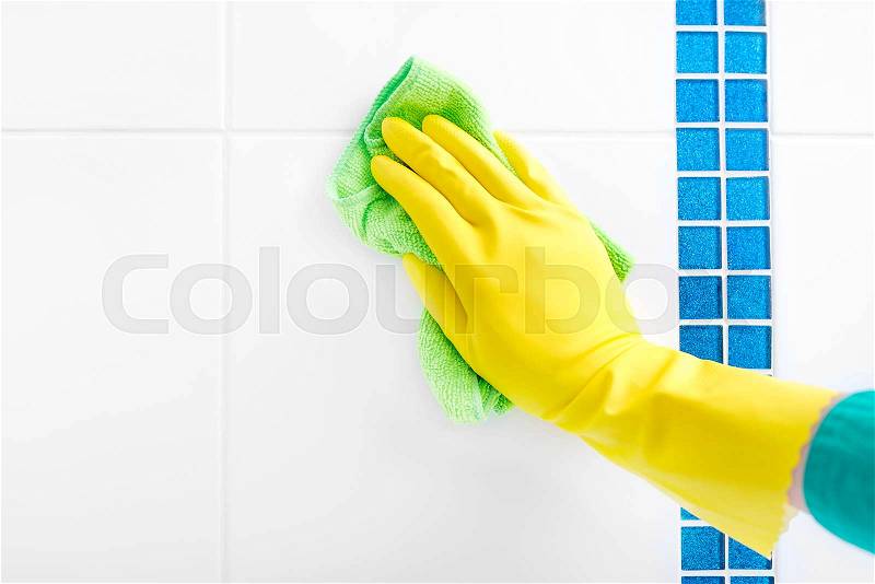 Hand in a yellow glove wash the tiles. Close-up, stock photo