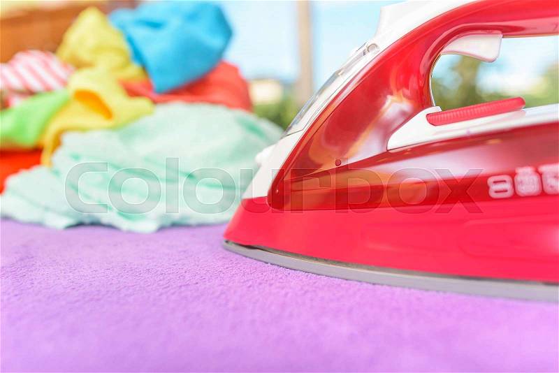 Iron and pile of clothes for ironing, stock photo