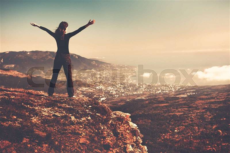 Woman standing on top of a mountain, back view, stock photo