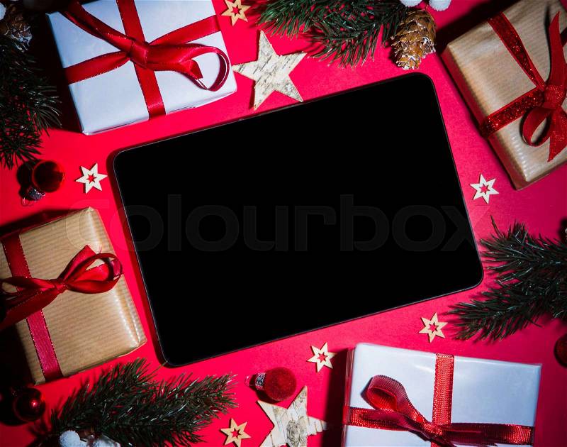 Tablet and tablet in Christmas red background with tree, gift and decoration, stock photo