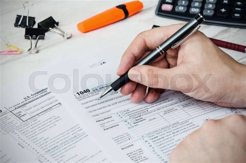 Man filling US tax form. tax form us business income office hand fill concept, stock photo