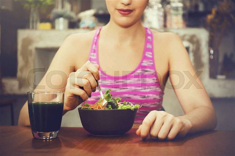 Attractive fitness woman is eating salad with healthy glass of juice - Fitness and Diet concept, stock photo