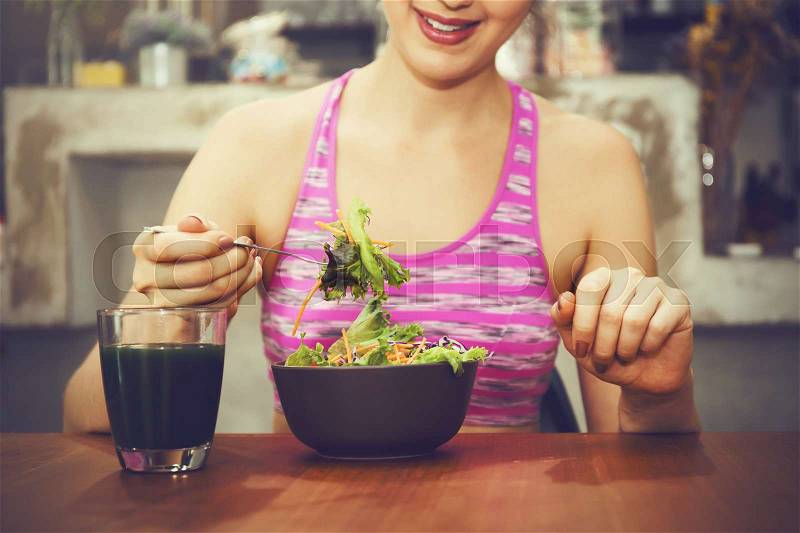 Attractive fitness woman is eating salad with healthy glass of juice - Fitness and Diet concept, stock photo