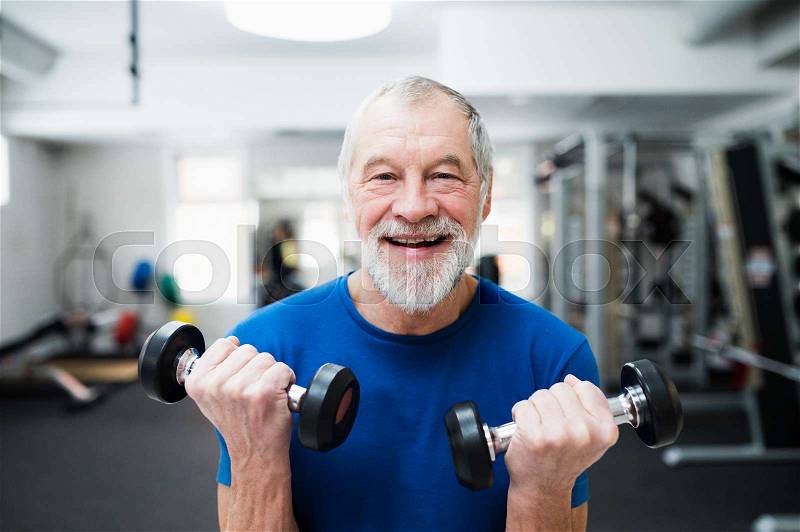 Senior man in sports clothing in gym working out with weights, stock photo