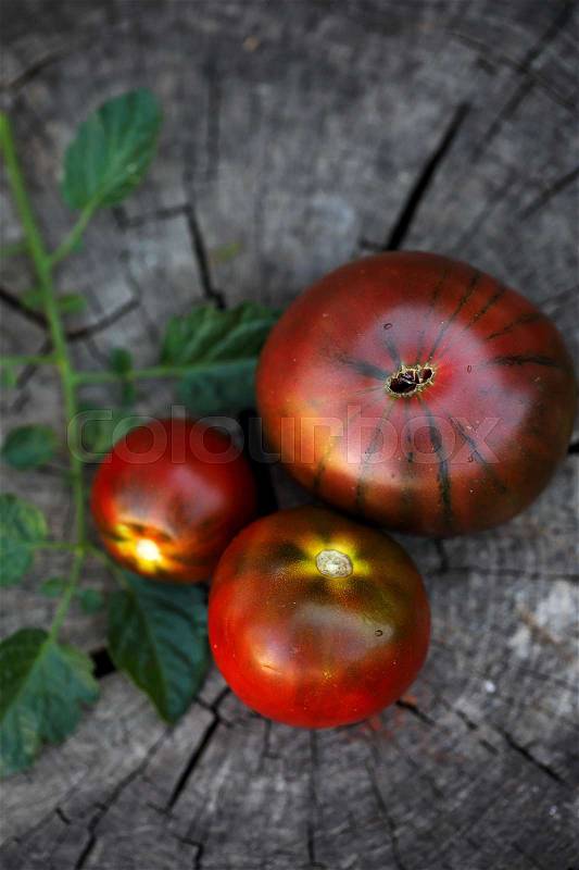 Organic Black tomato- kumato on the wood background, stock photo