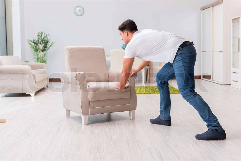 Man moving furniture at home, stock photo