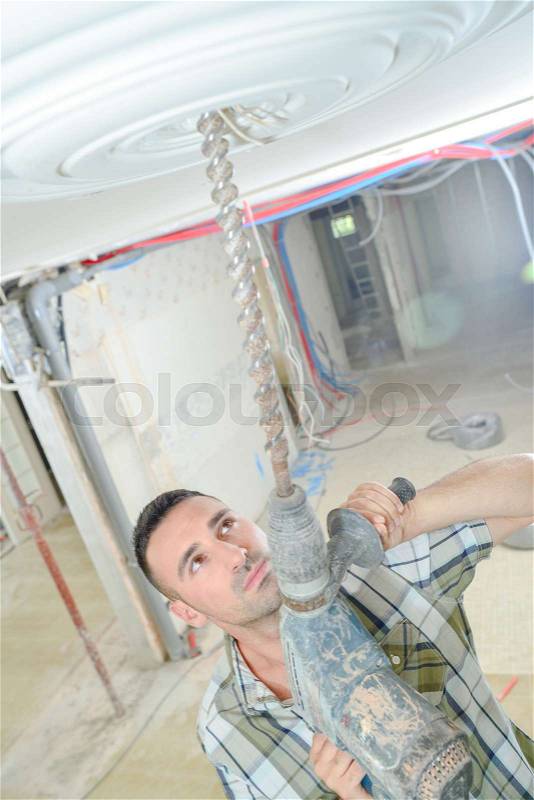 Man drilling ceiling rose, stock photo