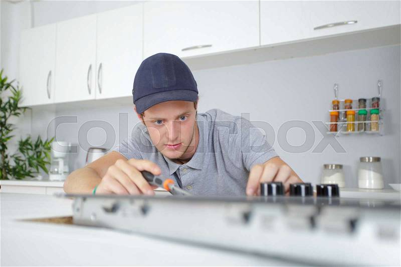 Young man fitting kitchen hob, stock photo