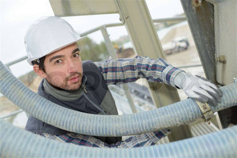 Man fitting jubilee clip on flexible pipe, stock photo