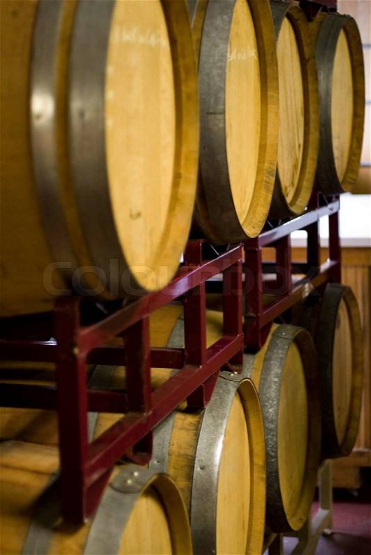 A vineyard cellar where barrels of wine age in stacked rows, stock photo