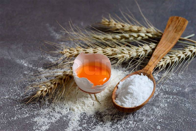 Baking powder in a wooden spoon and baking ingredients\, stock photo