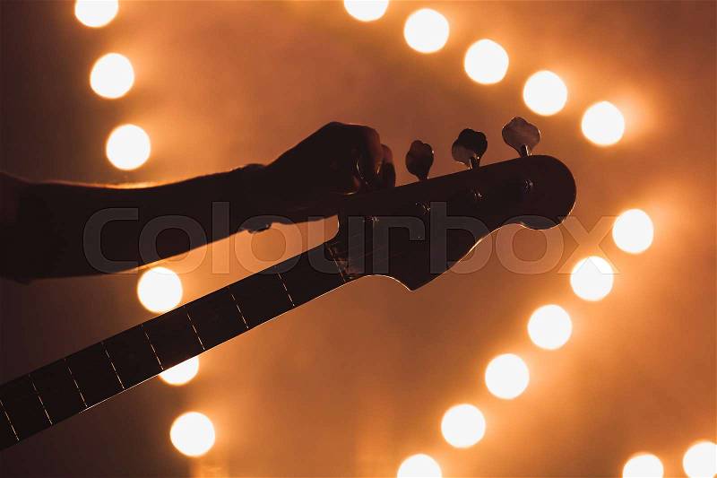 Live music background, guitarist tunes electric bass guitar, close-up silhuette photo with soft selective focus, stock photo