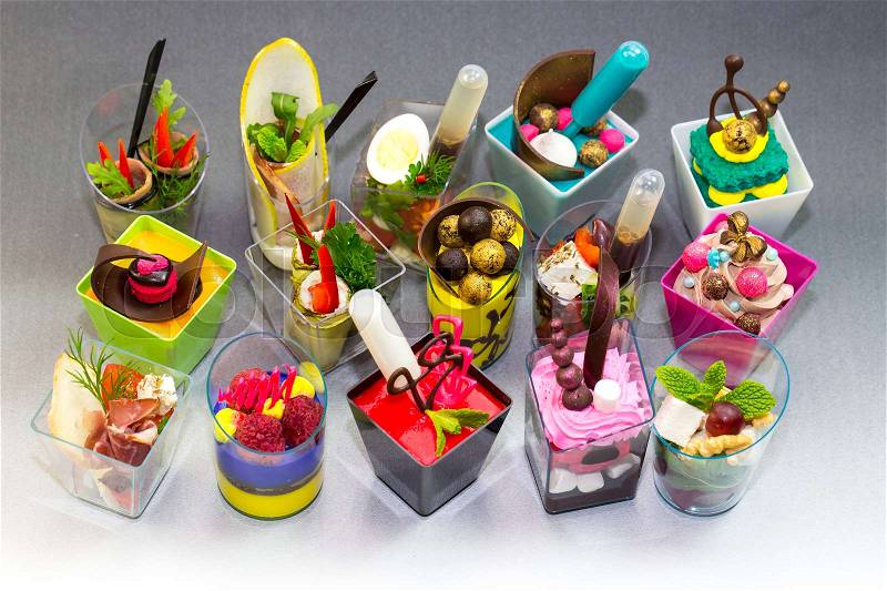 Mini desserts and meat canapes vegetable snacks in plastic cups canaps, stock photo