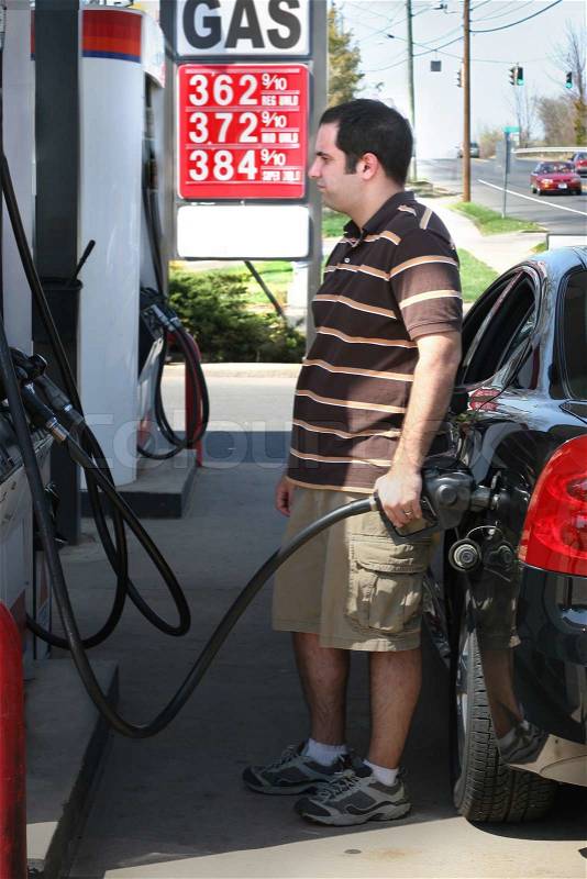 A man pumping high priced gas into his car with a disgusted look on his face, stock photo