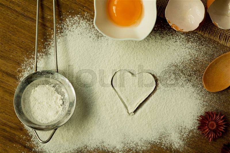Heart drawn in flour surrounded by ingredients for cooking, stock photo