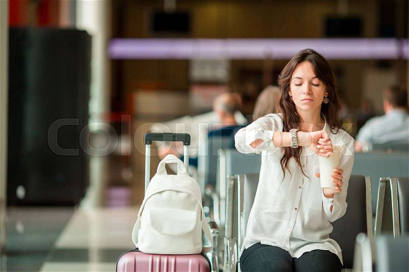 Woman in an airport lounge waiting for flight. Caucasian tourist looking for time in the waiting room, stock photo