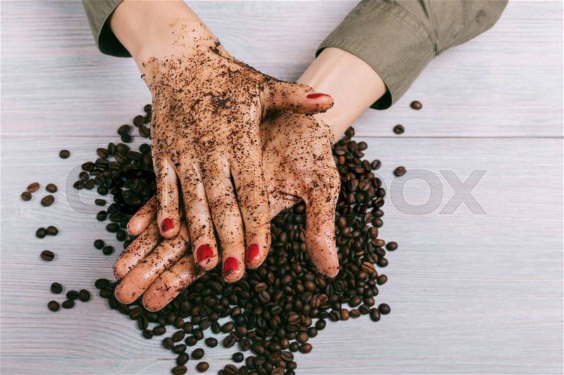 Woman applies coffee scrub on hands, top view, stock photo