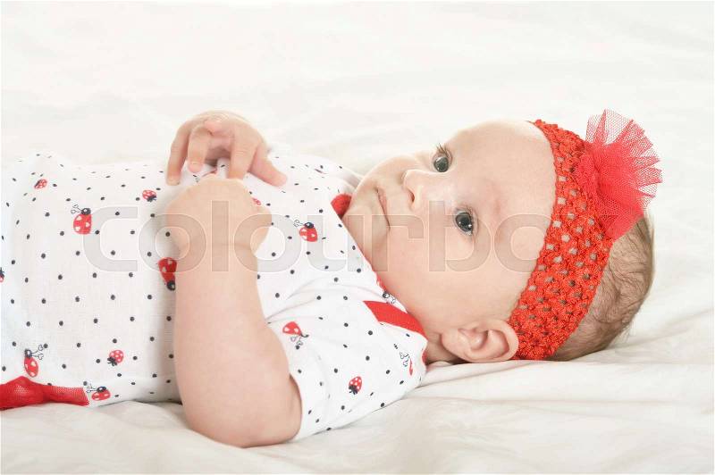 Adorable baby girl in cute clothes on blanket, stock photo