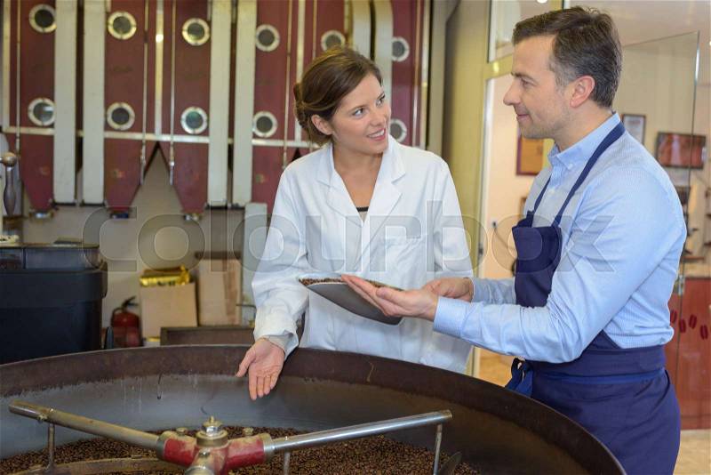 Man and lady looking at produce in industrial mixer, stock photo
