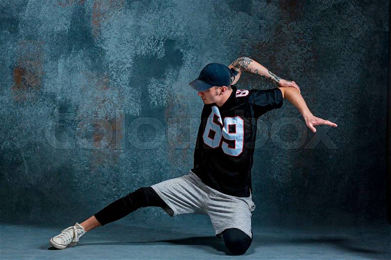 Young man break dancing on blue studio background, stock photo