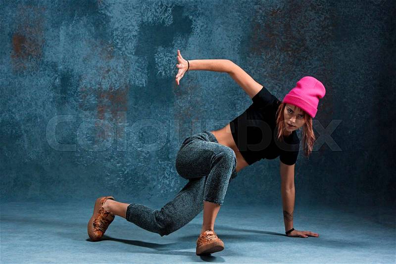 Young girl break dancing on blue studio background, stock photo
