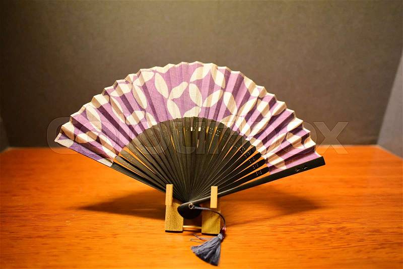 Purple Japanese folding fan on the wooden table, stock photo