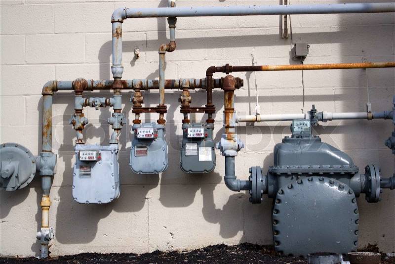 Old natural gas utility pipes and meters in an urban commercial setting, stock photo