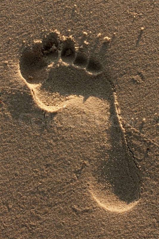 A single foot print imprinted in the sand on the beach, stock photo