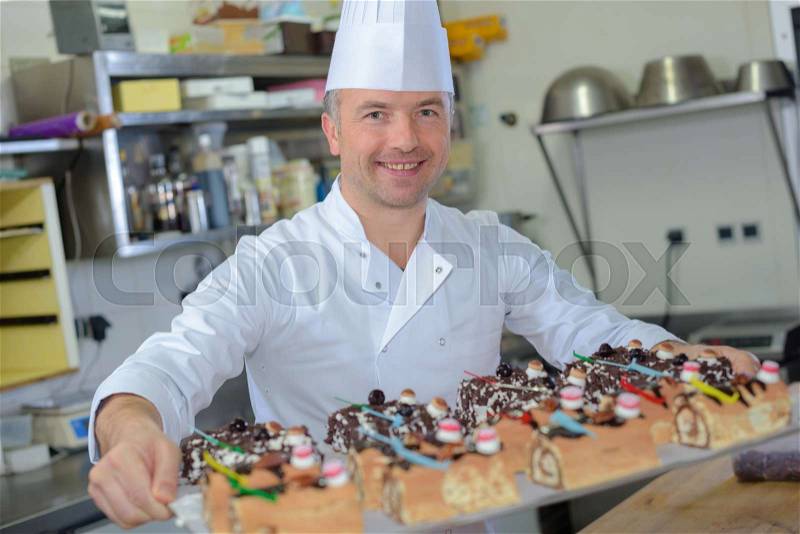 Pastry chef holding delicious looking cakes and pastries, stock photo