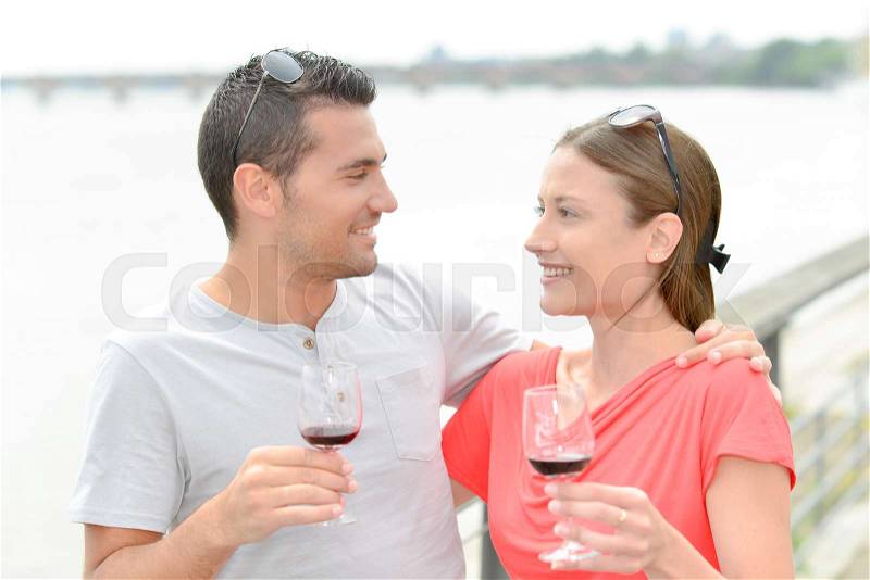 Couple enjoying wine by the river, stock photo