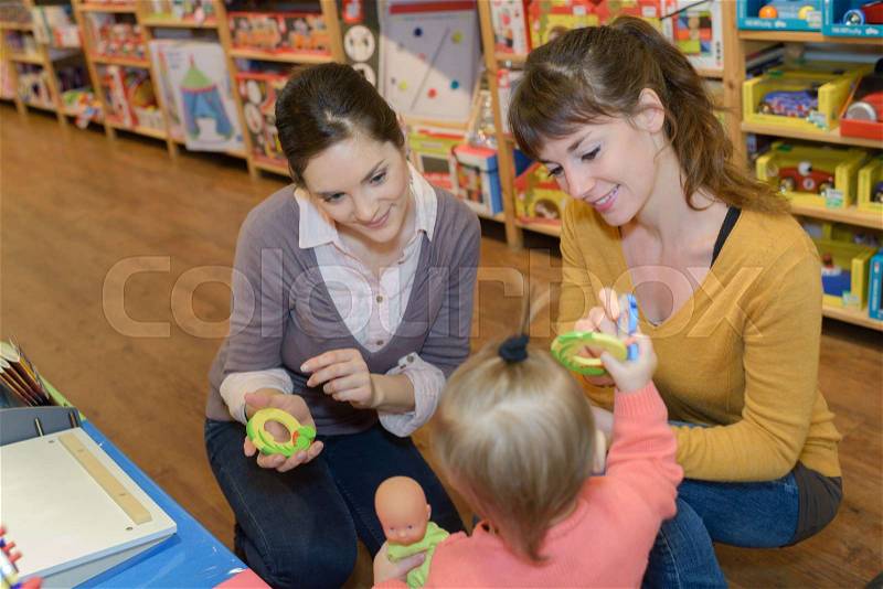 Mother and daughter with attractive vendor in toy store, stock photo