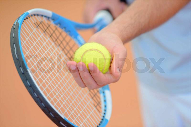 Closeup of hands holding tennis racket and ball, poised to serve, stock photo