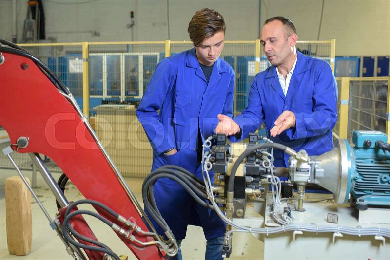 Engineers looking at hydraulic arm mechanicsm, stock photo