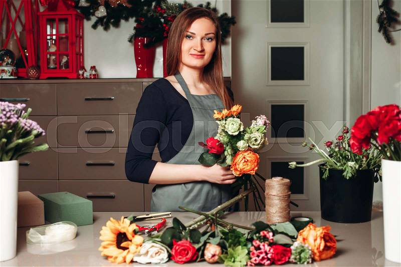 Female florist working with flowers while she made decorative bouquet, stock photo