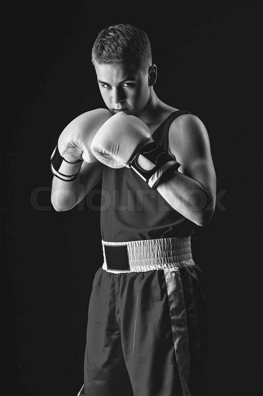 Young handsome boxer sportsman in white boxing gloves on black backgound. Copy space. Monochrome photo, stock photo