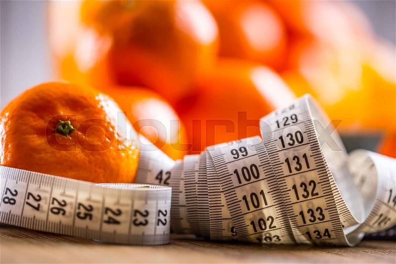 Fresh tropical fruit and measure tape.Tangerines, peeled tangerine and tangerine slices on a blue cloth. Mandarine juice, stock photo