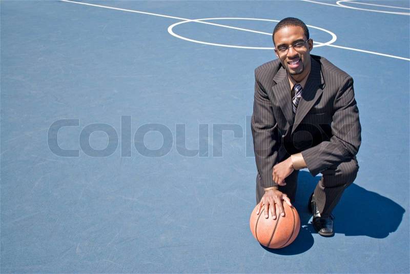 A young man in a business suit posing in the empty basketball court with lots of copyspace, stock photo