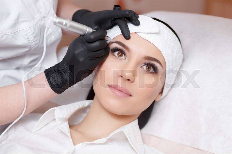 Permanent makeup. Permanent tattooing of eyebrows. Cosmetologist applying permanent make up on eyebrows- eyebrow tattoo, stock photo