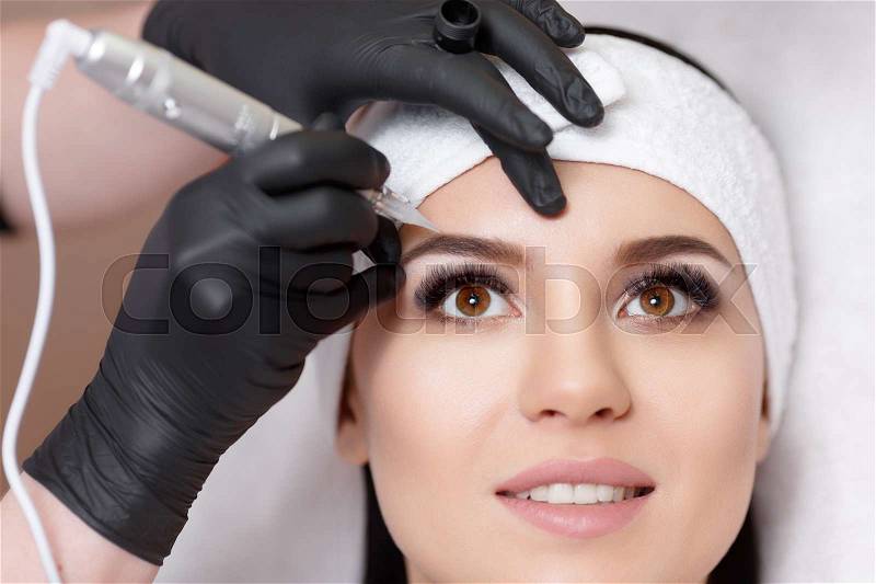 Permanent makeup. Permanent tattooing of eyebrows. Cosmetologist applying permanent make up on eyebrows- eyebrow tattoo, stock photo