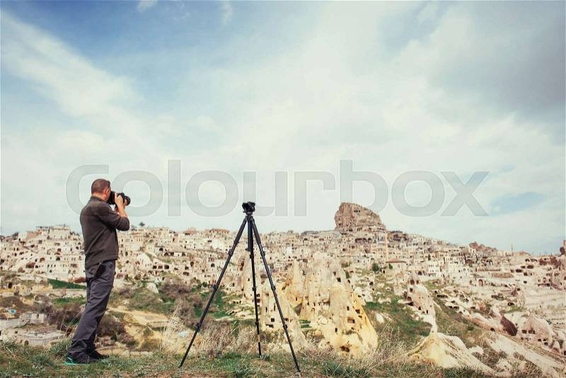 A man photographs the ancient city and the castle Uchhysar dug from the mountains. Cappadocia, Turkey, stock photo